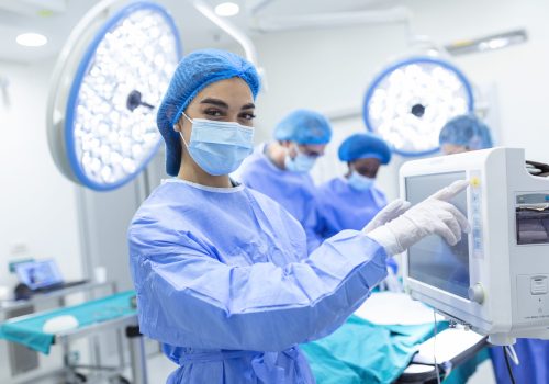 Anesthesiologist keeping track of vital functions of the body during cardiac surgery. Surgeon looking at medical monitor during surgery. Doctor checking monitor for patient health status.